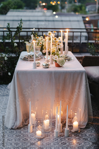 Banquet table is decorated with plates, cutlery, glasses and flower arrangements
