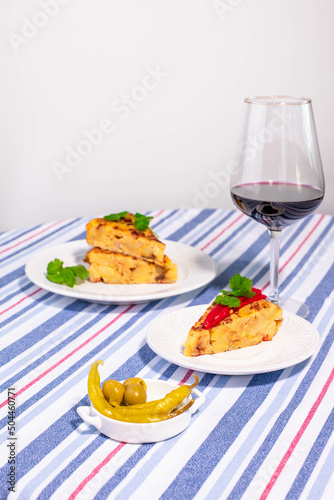 Traditional Spanish snack tortilla patatas served with red piquillo pepper and a glass of wine.