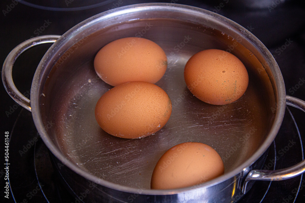 Chicken white eggs are boiled in boiling water in a metal saucepan Chicken white eggs are boiled in boiling water in a metal saucepan