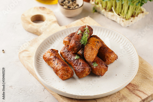 Traditional south european skinless sausages cevapcici made of ground meat and spices on white plate on light wooden board, with thyme and watercress salad photo