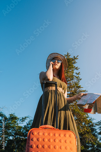 young red-haired girl calling with her smart phone for a taxi to pick her up at her resort. travel, summer holiday,