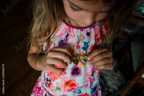 little girl looks at locket necklace