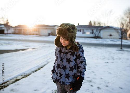 boy walks in snowy neighborhood during sunset photo