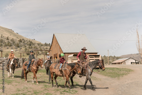 family of cowboys ride horses on a cattle ranch photo