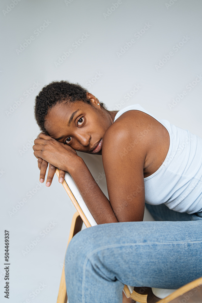 young melancholic black woman sitting on chair in studio young melancholic black woman sitting on chair in studio