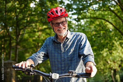Older Man with glasses rides Mountain bike on leisure cycle photo