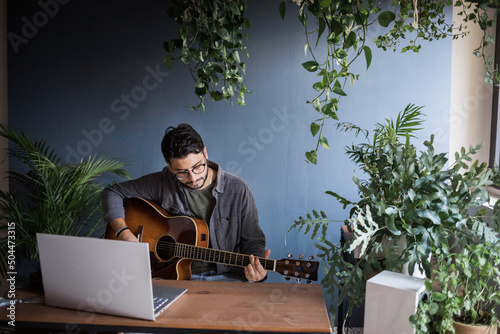 Headshot Of Musician Playing Classic Guitar Surrounded By Plants photo