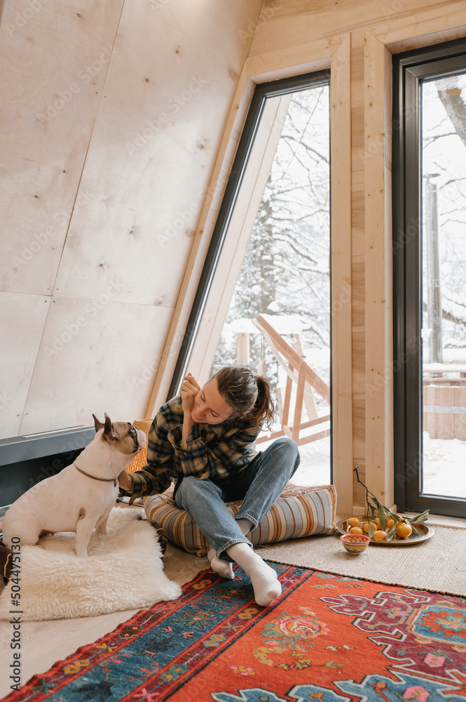 Woman stroking purebred dog on floor in A frame cabin Woman stroking purebred dog on floor in A frame cabin