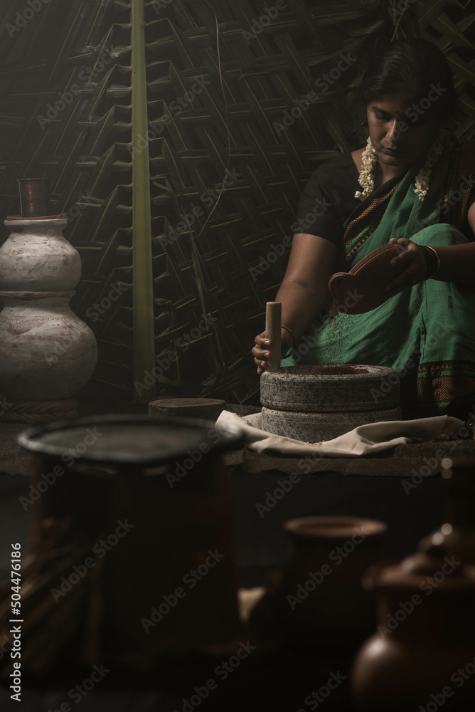 A woman grinding millet flour using grinding stone A woman grinding millet flour using grinding stone