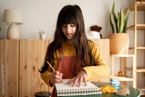 Kid drawing on sketch book from home