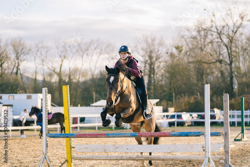 Female jockey on horse leaping over obstacle photo