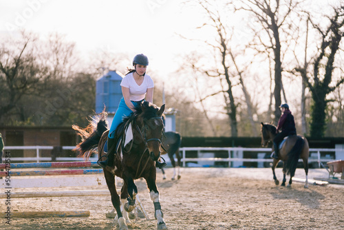 Active female equestrian riding purebred horse on arena photo