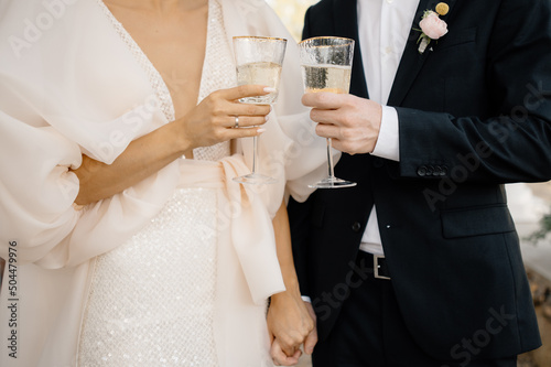 bride and groom holding hands and drink champagne photo