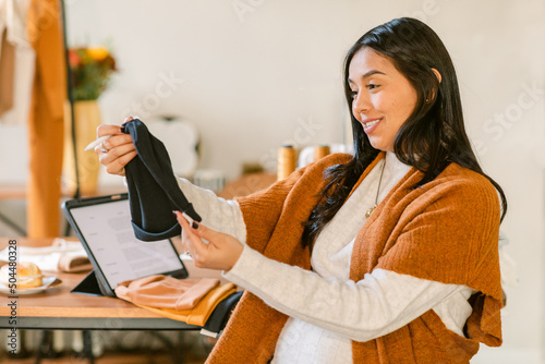 Excited pregnant woman looking at baby clothes photo