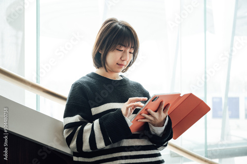 Young asian girl using digital tablet on the hall way stairs