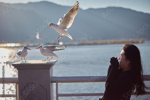 Funny Portrait Of Terrified Asian Woman Next To A Group Of Seagulls. photo