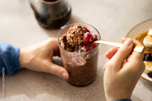 Woman eating healthy overnight oatmeal breakfast with fruit topping photo