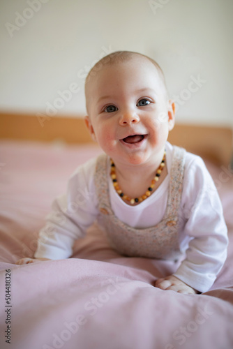 Cute baby crawling on bed looking at camera photo