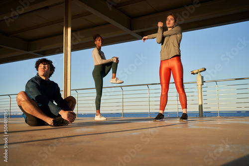 Sporty atheltes stretching on pier during training photo