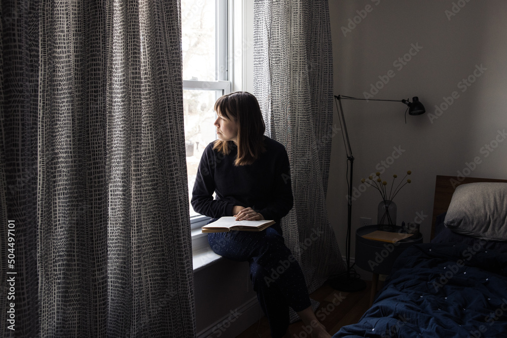 Woman writing a journal by the window Woman writing a journal by the window