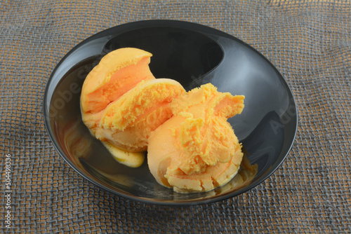 Valokuvatapetti Two scoops of orange sherbet with chocolate syrup topping in black bowl on gray