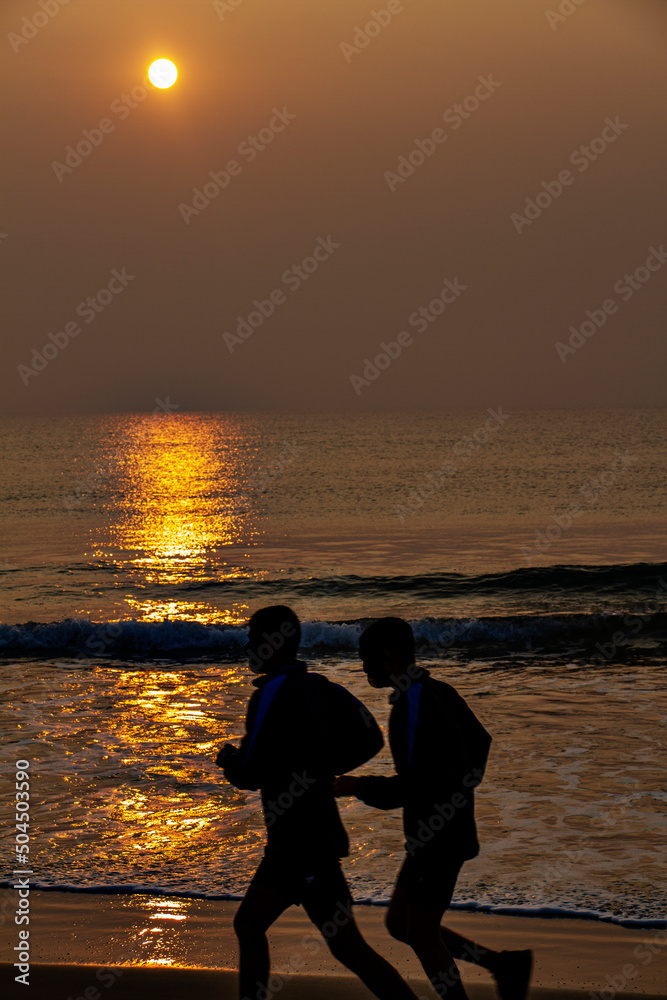 Fototapeta premium Silhouette of persons on the beach early morning