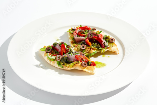 Tapas with avocado cream, anchovy, paprika and kalamata olives on focaccia. Bruschetta with guacamole and anchovy isolated on white background. Appetizer contemporary concept. Fish antipasti.