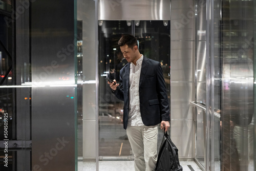 Businessman using a mobile phone in the company lift