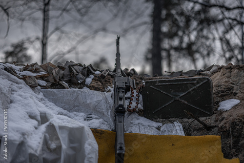 Close up of army trench with weapon among dark trees photo