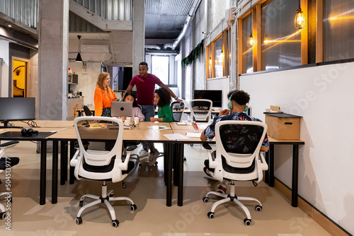 Smiling multiracial coworkers making project on laptop photo