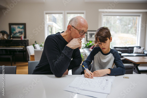 Mature man helping kid with schoolwork