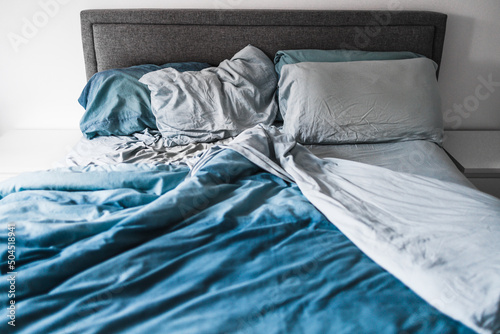 improving your sleep or couple life, queen size bed lookng messy on one side and tidy on the other with light blue quilt cover and sheets