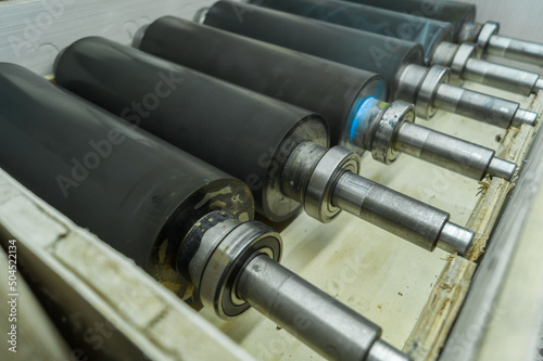 Used printing shafts for flexographic printing press. A set of rubberized knurling shafts in a wooden box. Spares. Selective focus
