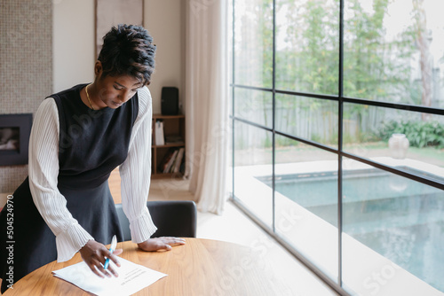 Professional confident woman at home reading and signing documents photo