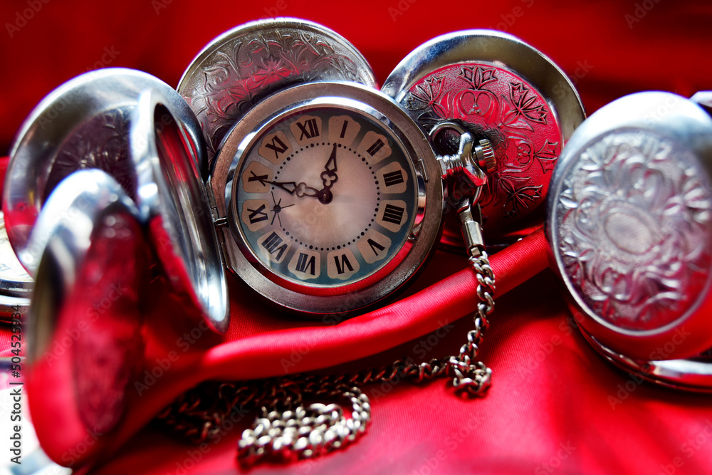 Vintage collection of antique pocket watches on red crumpled background