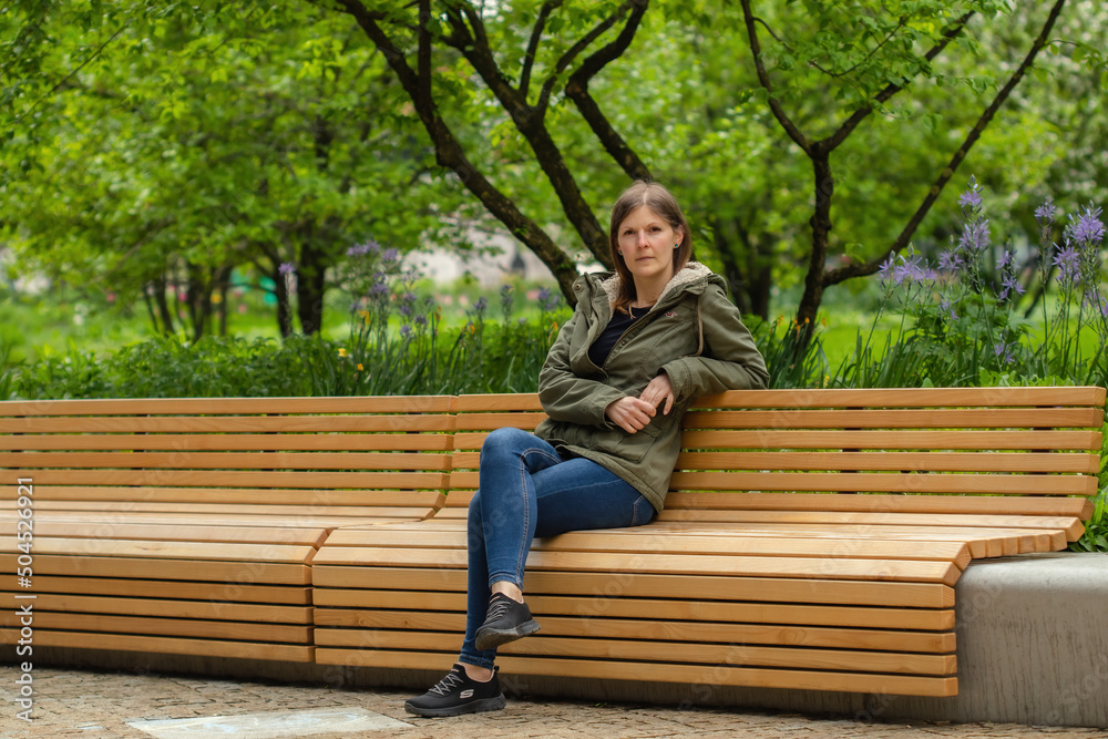 Young woman sitting on a bench in a city park. Conceptual photo. Portrait of a young woman.