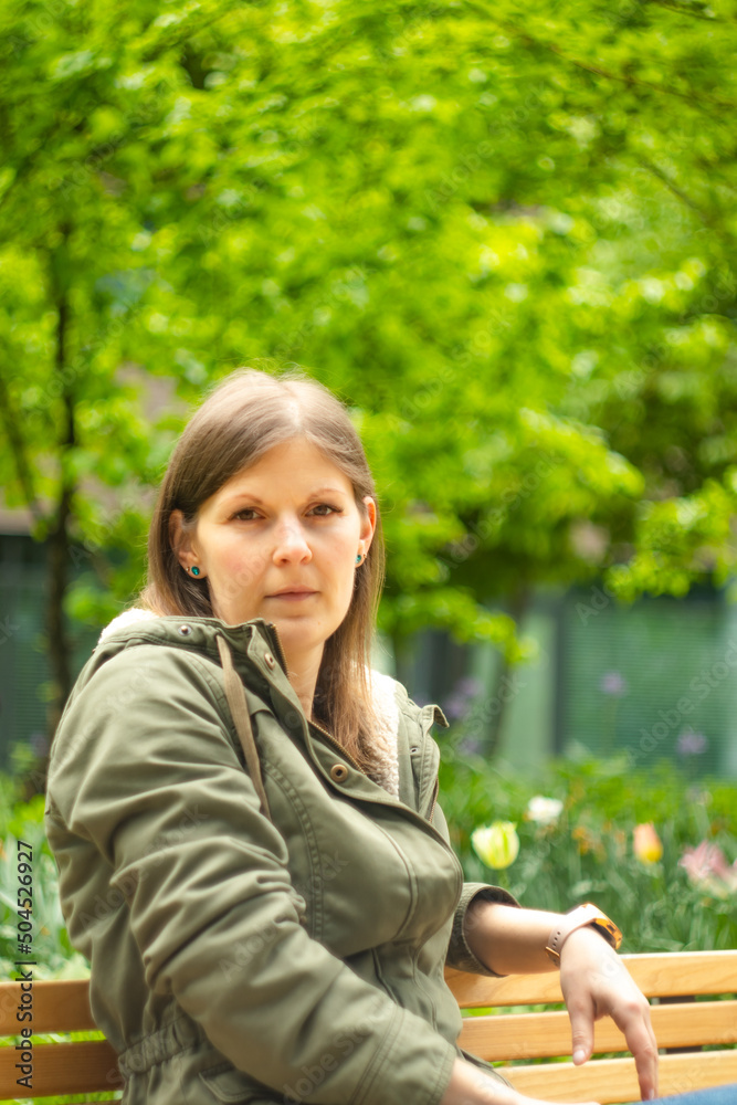 Young woman sitting on a bench in a city park. Conceptual photo. Portrait of a young woman. Young woman sitting on a bench in a city park. Conceptual photo. Portrait of a young woman.
