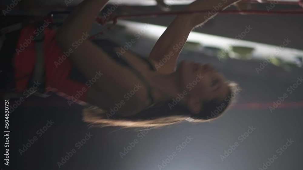 Handheld, female climber training on a climbing wall, young woman practicing rock-climbing and moving up, vertical video, rises using insurance, cinematic light. Handheld, female climber training on a climbing wall, young woman practicing rock-climbing and moving up, vertical video, rises using insurance, cinematic light.