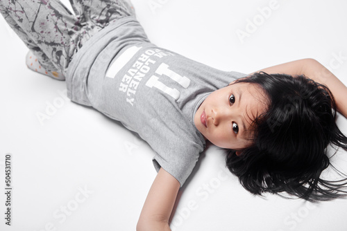Closeup of asian kid entertaining himself, lying on the ground