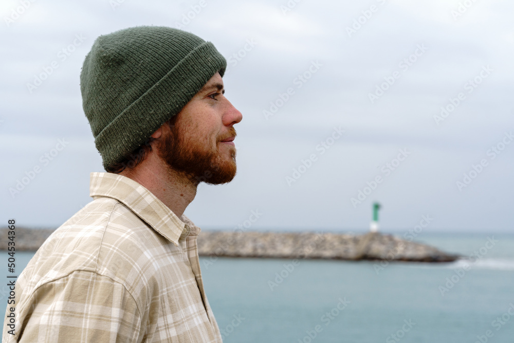 Red-haired man with beard and wool hat by the sea Red-haired man with beard and wool hat by the sea