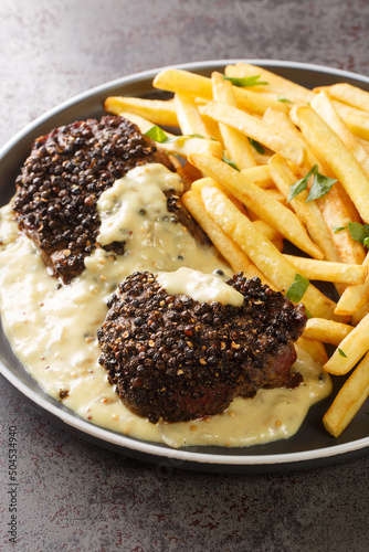 Homemade Steak Au Poivre with Pepper Sauce served with french fries close-up in a plate on the table. Verttical photo