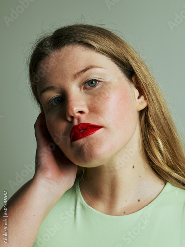 young blond female portrait with soft olive green background - red lip