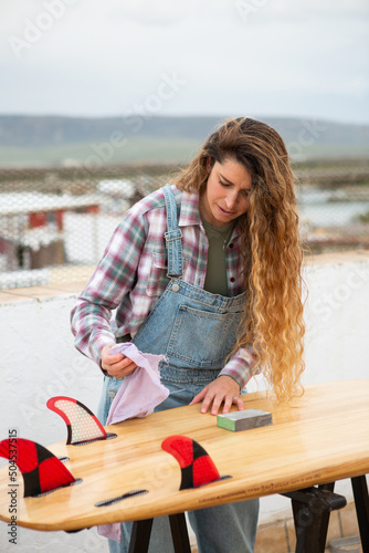 Surfer wiping her surfboard down during repairs photo