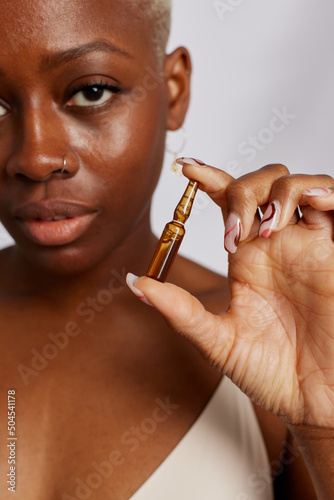Woman showing ampoule of moisturizing serum photo