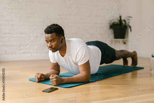 Fit male doing plank exercises indoors photo