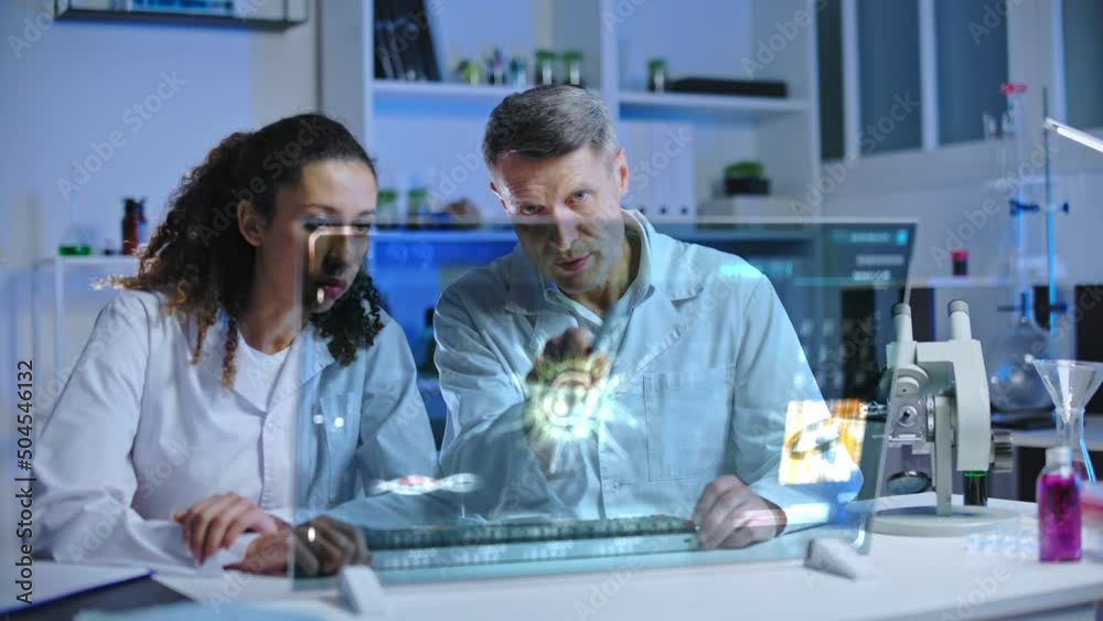 Lab scientist and assistant studying virus cell hologram, vaccine development Lab scientist and assistant studying virus cell hologram, vaccine development