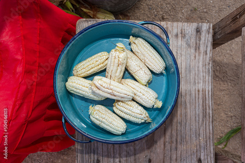 Pewter pot with white corn inside on a wooden base photo