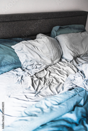 improving your sleep or couple life, messy bed with blue quilt cover and sheets looking crumpled and untidy