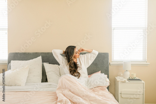 Relaxed woman in bed at luminous bedroom photo