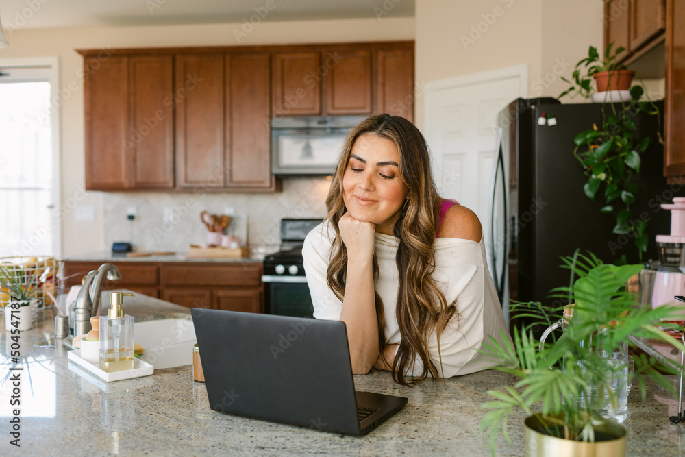 Smiling woman making video chat on laptop in kitchen Smiling woman making video chat on laptop in kitchen
